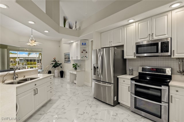 kitchen with a sink, marble finish floor, appliances with stainless steel finishes, light countertops, and backsplash