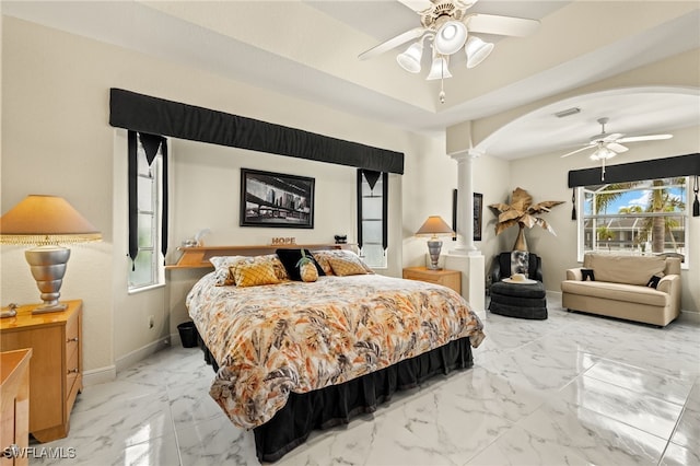 bedroom with arched walkways, baseboards, marble finish floor, a raised ceiling, and decorative columns