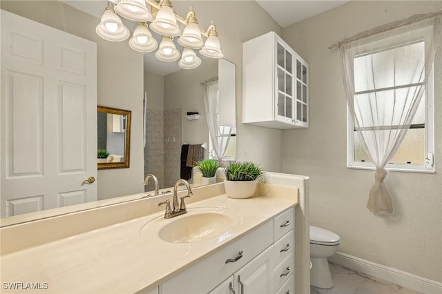 bathroom with marble finish floor, toilet, vanity, and baseboards