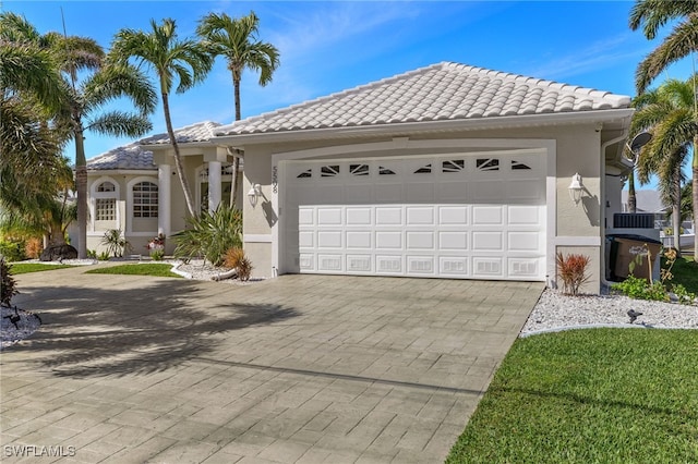 view of front facade with a garage, a tiled roof, decorative driveway, and stucco siding