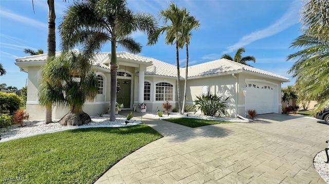 view of front facade with decorative driveway, a tile roof, stucco siding, a front yard, and a garage