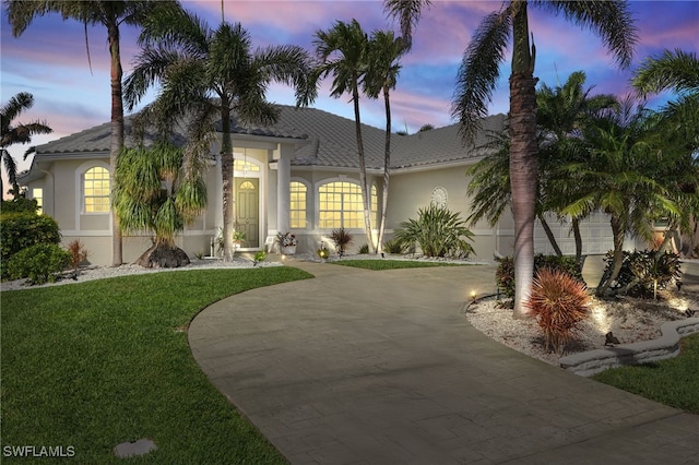 view of front facade with a garage, driveway, a front lawn, and stucco siding