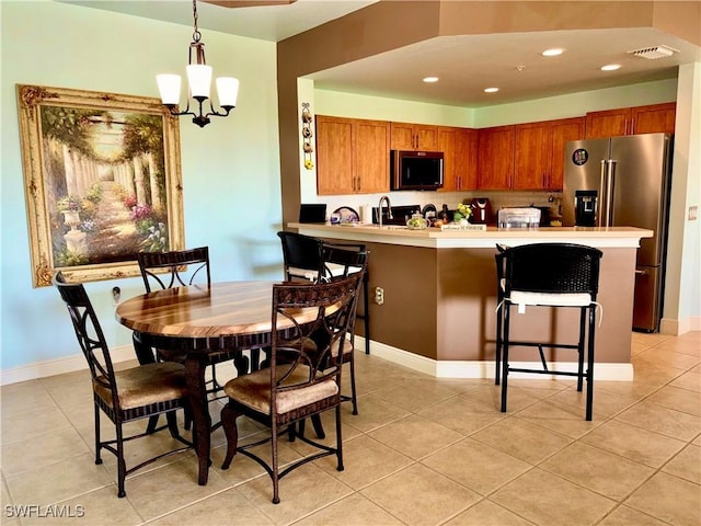 kitchen featuring high quality fridge, a breakfast bar, decorative light fixtures, light tile patterned floors, and kitchen peninsula