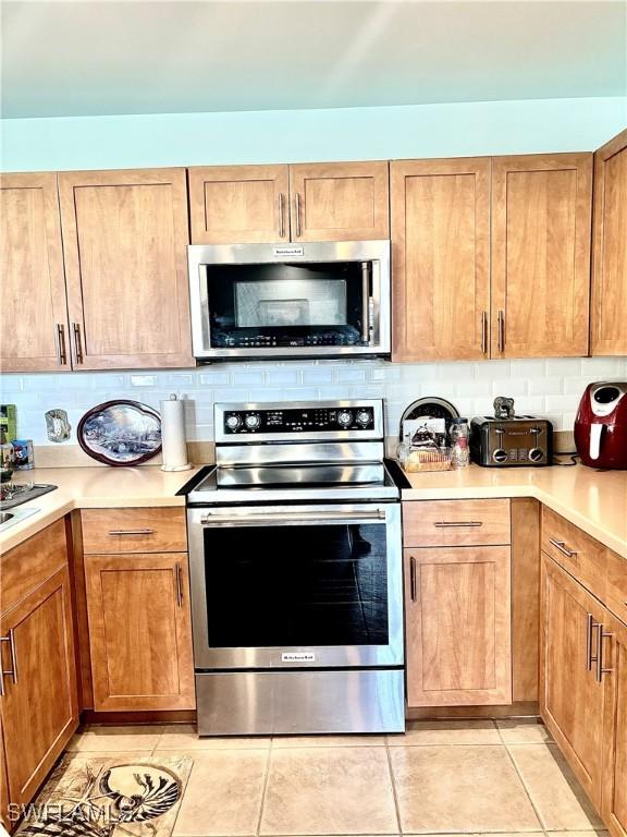 kitchen with tasteful backsplash, appliances with stainless steel finishes, and light tile patterned floors