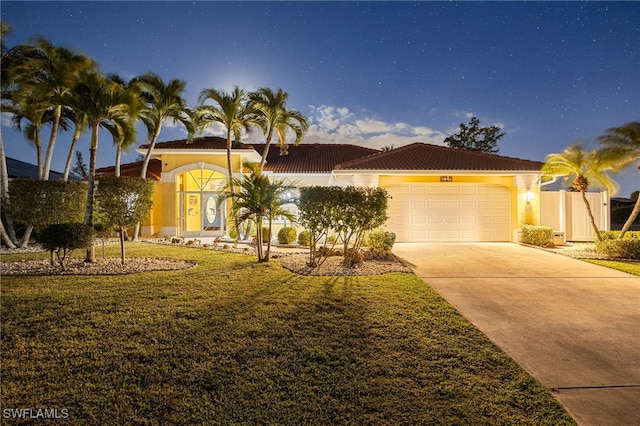 mediterranean / spanish home with a garage and a front lawn