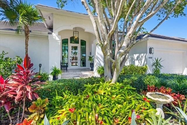 property entrance with a porch, an attached garage, and stucco siding