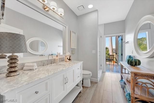 bathroom with toilet, baseboards, wood finished floors, and vanity