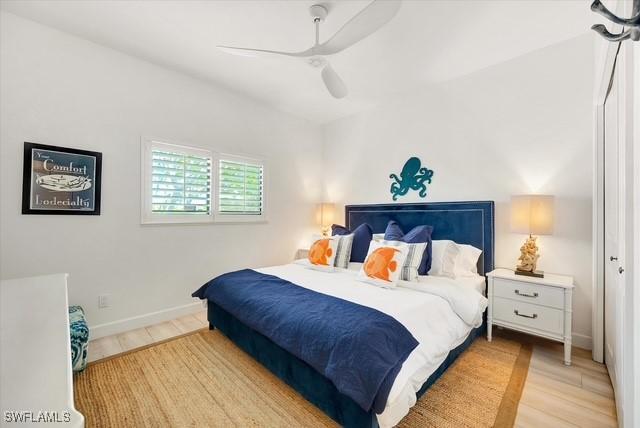 bedroom with light wood finished floors, baseboards, and a ceiling fan