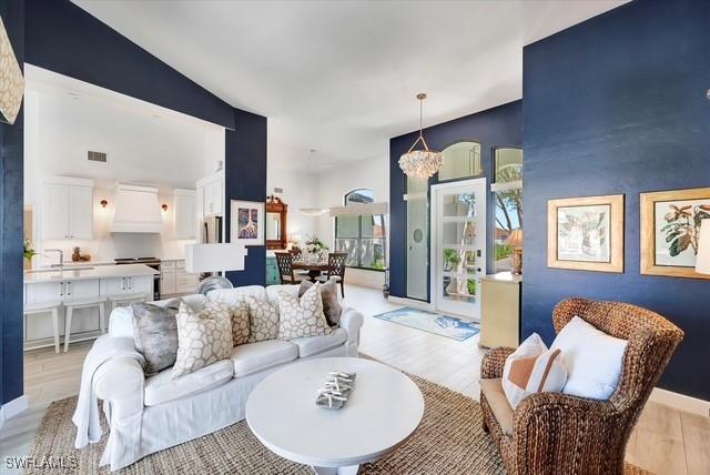 living area featuring light wood-style flooring, visible vents, and a notable chandelier