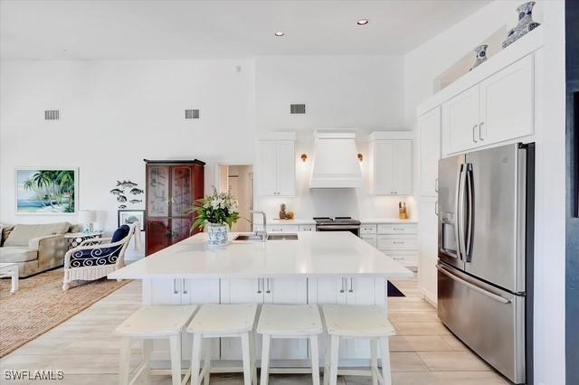 kitchen featuring stainless steel appliances, premium range hood, a sink, and visible vents