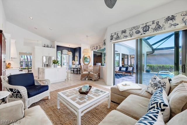 living area featuring light wood-type flooring, a sunroom, vaulted ceiling, and recessed lighting