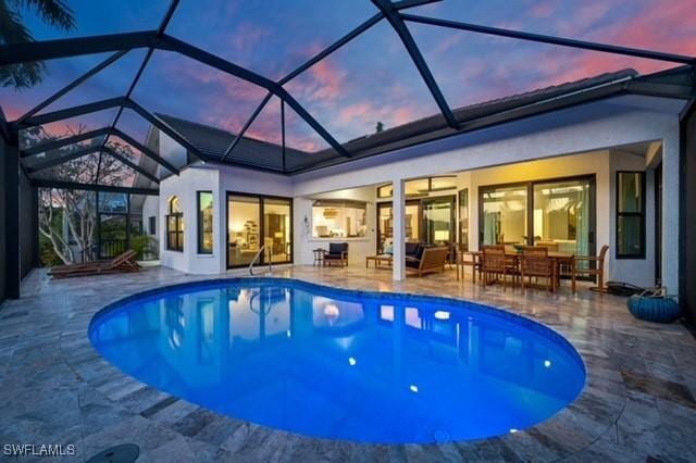 pool at dusk with an outdoor pool and a patio