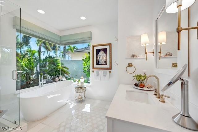 full bathroom with a stall shower, a soaking tub, vanity, and recessed lighting