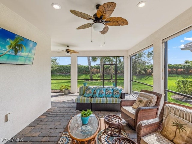 sunroom / solarium featuring a healthy amount of sunlight and ceiling fan