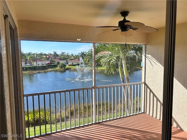 unfurnished sunroom featuring a water view and a ceiling fan