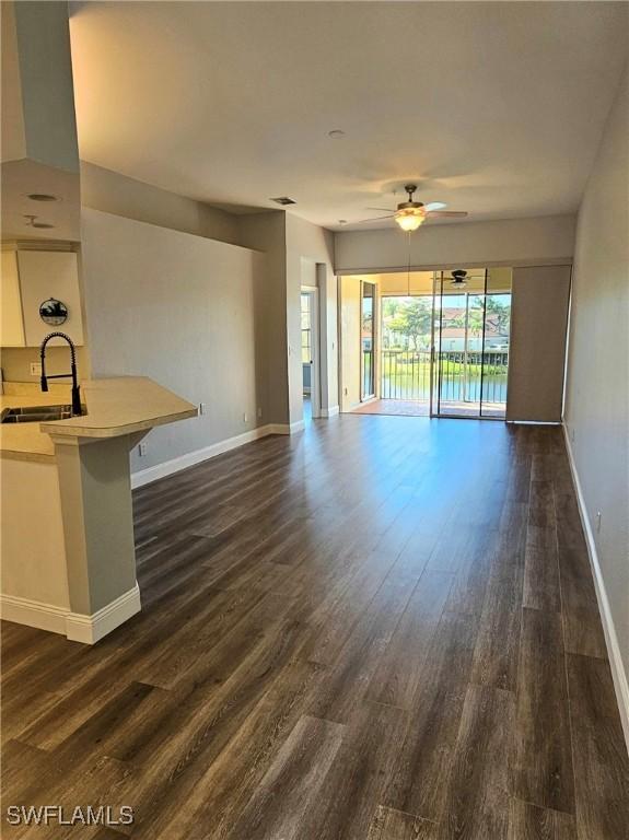 23861 Costa Del Sol Rd Unit 203, Estero, FL 34135 - unfurnished living room featuring a sink, baseboards, ceiling fan, and dark wood-type flooring