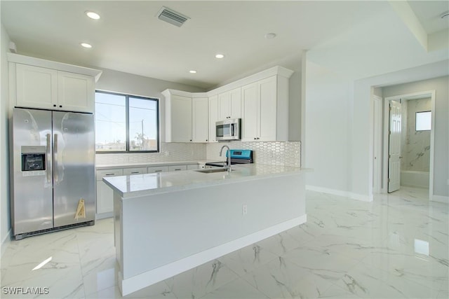 kitchen with sink, white cabinetry, tasteful backsplash, kitchen peninsula, and stainless steel appliances