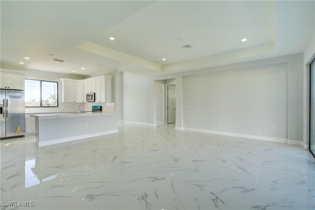 unfurnished living room with a raised ceiling and sink