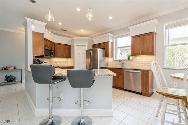 kitchen featuring light tile patterned floors, stainless steel appliances, hanging light fixtures, light stone countertops, and ornamental molding