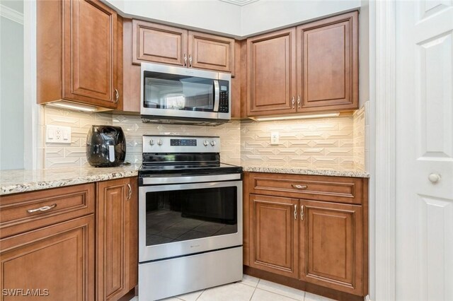 2291 Granby Dr, Lehigh Acres, FL 33973 - kitchen featuring brown cabinets, backsplash, light stone countertops, and appliances with stainless steel finishes