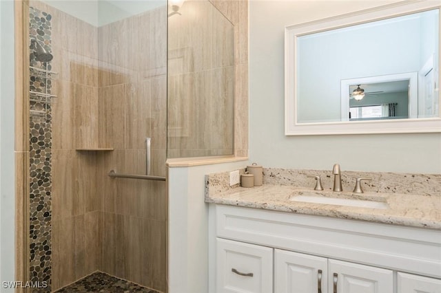 bathroom with a tile shower and vanity