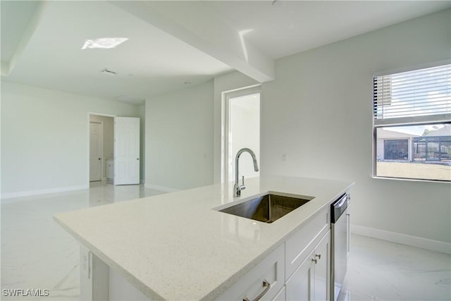 kitchen with an island with sink, sink, white cabinets, stainless steel dishwasher, and light stone counters