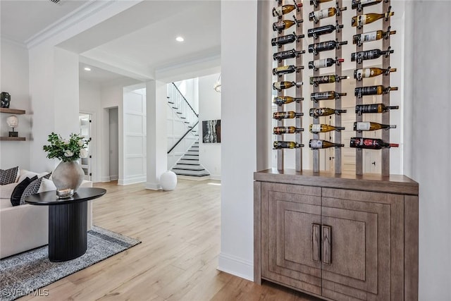 wine room featuring recessed lighting, baseboards, crown molding, and light wood finished floors