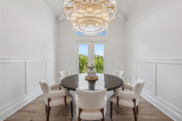 dining space featuring light wood-style floors, a decorative wall, and french doors