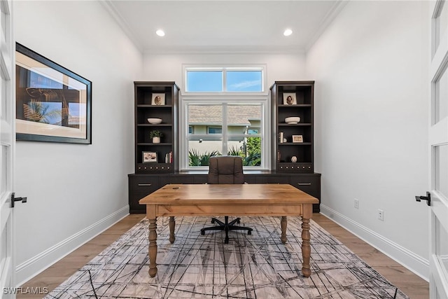 office featuring light wood-style floors, baseboards, a wealth of natural light, and crown molding