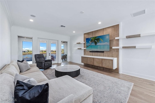 living area with french doors, crown molding, visible vents, wood finished floors, and baseboards