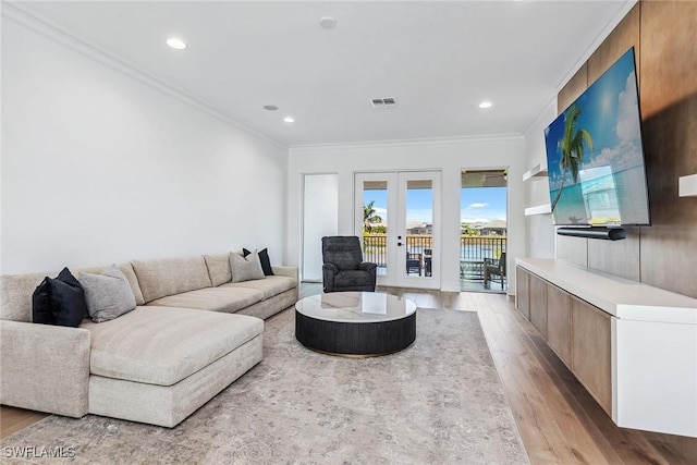 living room with ornamental molding, french doors, visible vents, and light wood-style floors