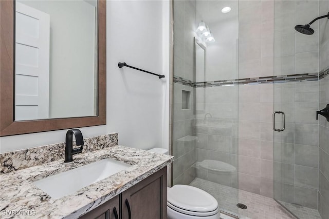 full bath with vanity, a shower stall, and toilet