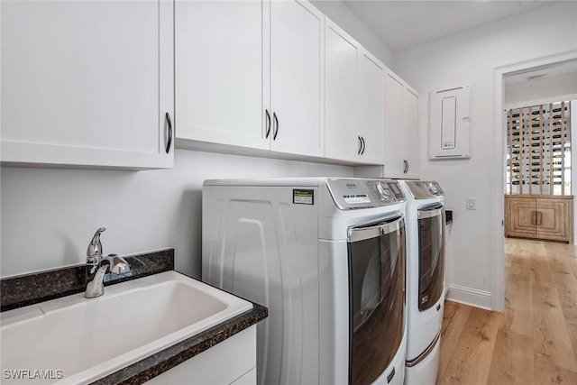 clothes washing area featuring cabinet space, baseboards, washer and clothes dryer, light wood-style flooring, and a sink