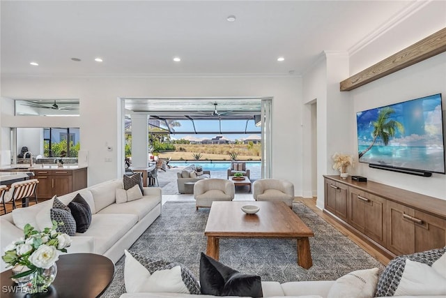 living area with ornamental molding, recessed lighting, a sunroom, and light wood-style floors