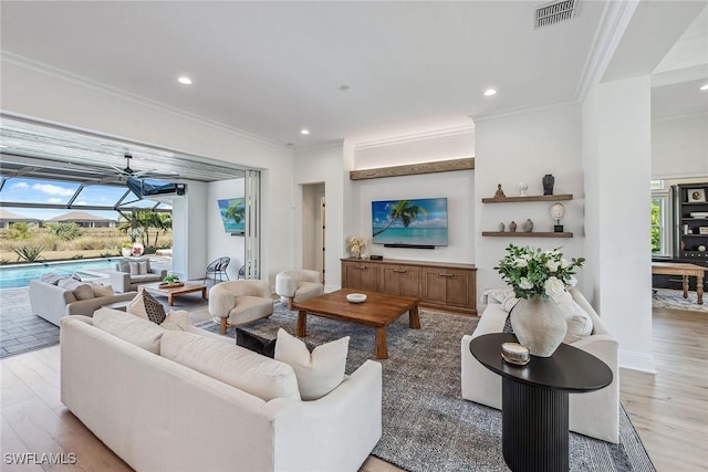 living area with a sunroom, light wood-style flooring, visible vents, and crown molding