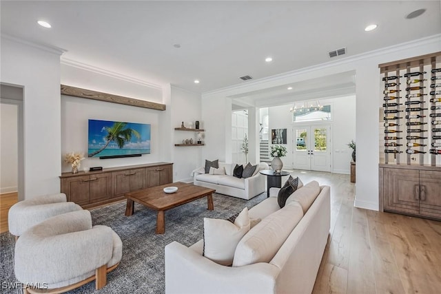 living area featuring light wood finished floors, ornamental molding, and visible vents