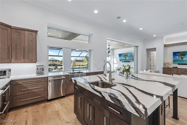 kitchen featuring a sink, light wood-style floors, ornamental molding, and stainless steel dishwasher