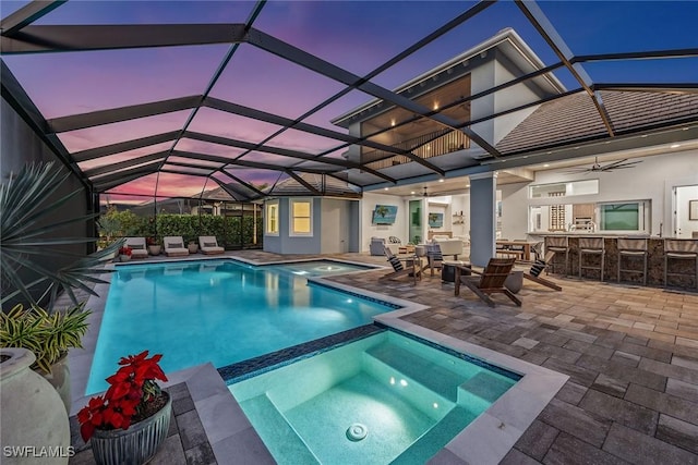 view of pool featuring outdoor dry bar, a patio area, a lanai, and a pool with connected hot tub