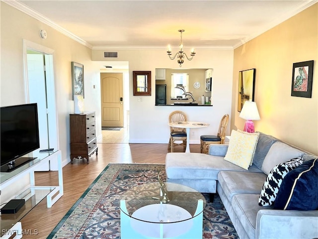 living room with hardwood / wood-style flooring, ornamental molding, and a notable chandelier