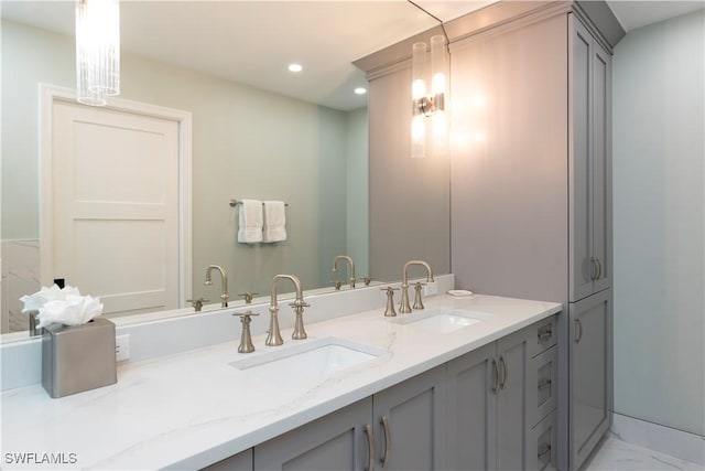 bathroom featuring marble finish floor, double vanity, a sink, and recessed lighting