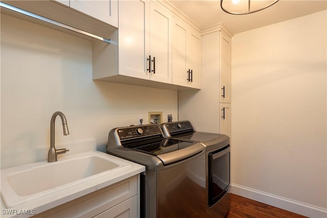 clothes washing area featuring cabinet space, a sink, washing machine and dryer, baseboards, and dark wood-style floors