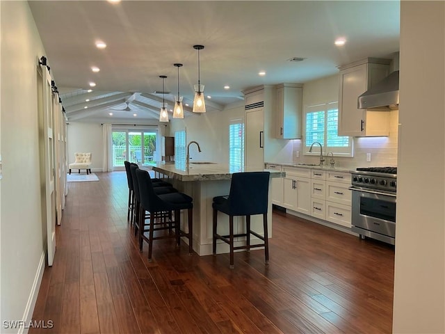 kitchen with recessed lighting, a sink, wall chimney range hood, and premium appliances