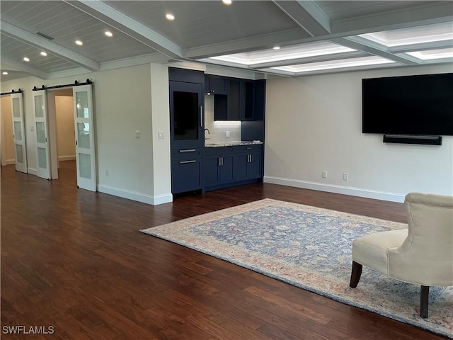 living room with baseboards, beam ceiling, dark wood finished floors, and a barn door