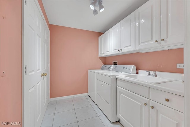 clothes washing area with cabinets, sink, light tile patterned floors, and washing machine and clothes dryer