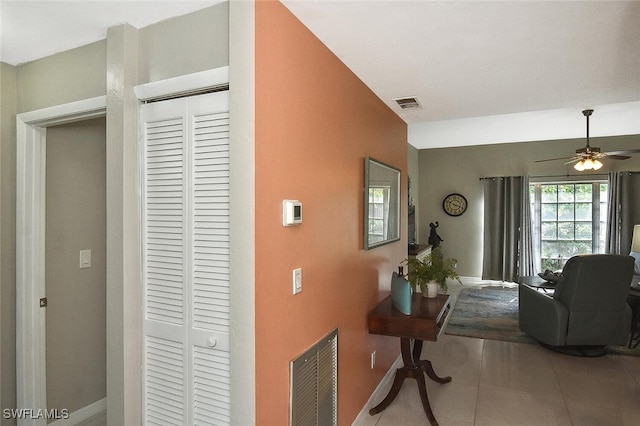 corridor featuring baseboards, visible vents, and tile patterned floors