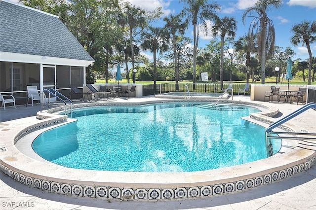 community pool with a sunroom, a patio, and fence