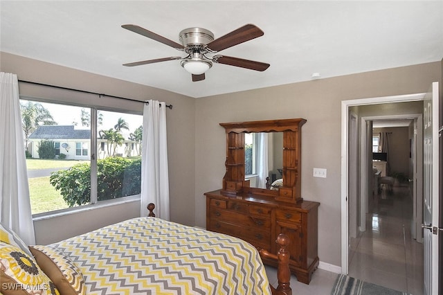 tiled bedroom featuring a ceiling fan, multiple windows, and baseboards