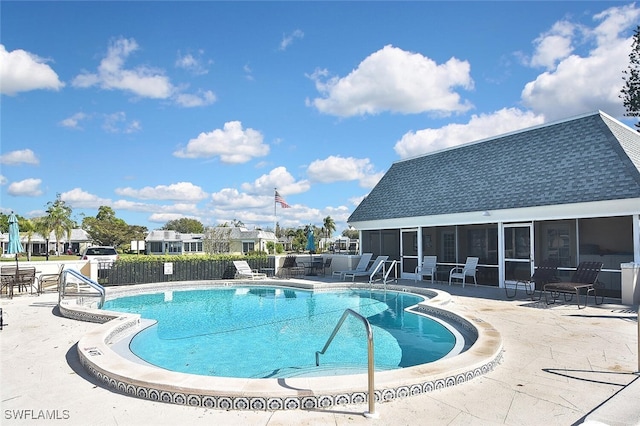 community pool with a patio area, fence, and a sunroom