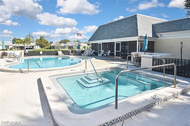 pool with a patio, fence, and a sunroom