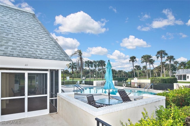 community pool with a patio area and fence